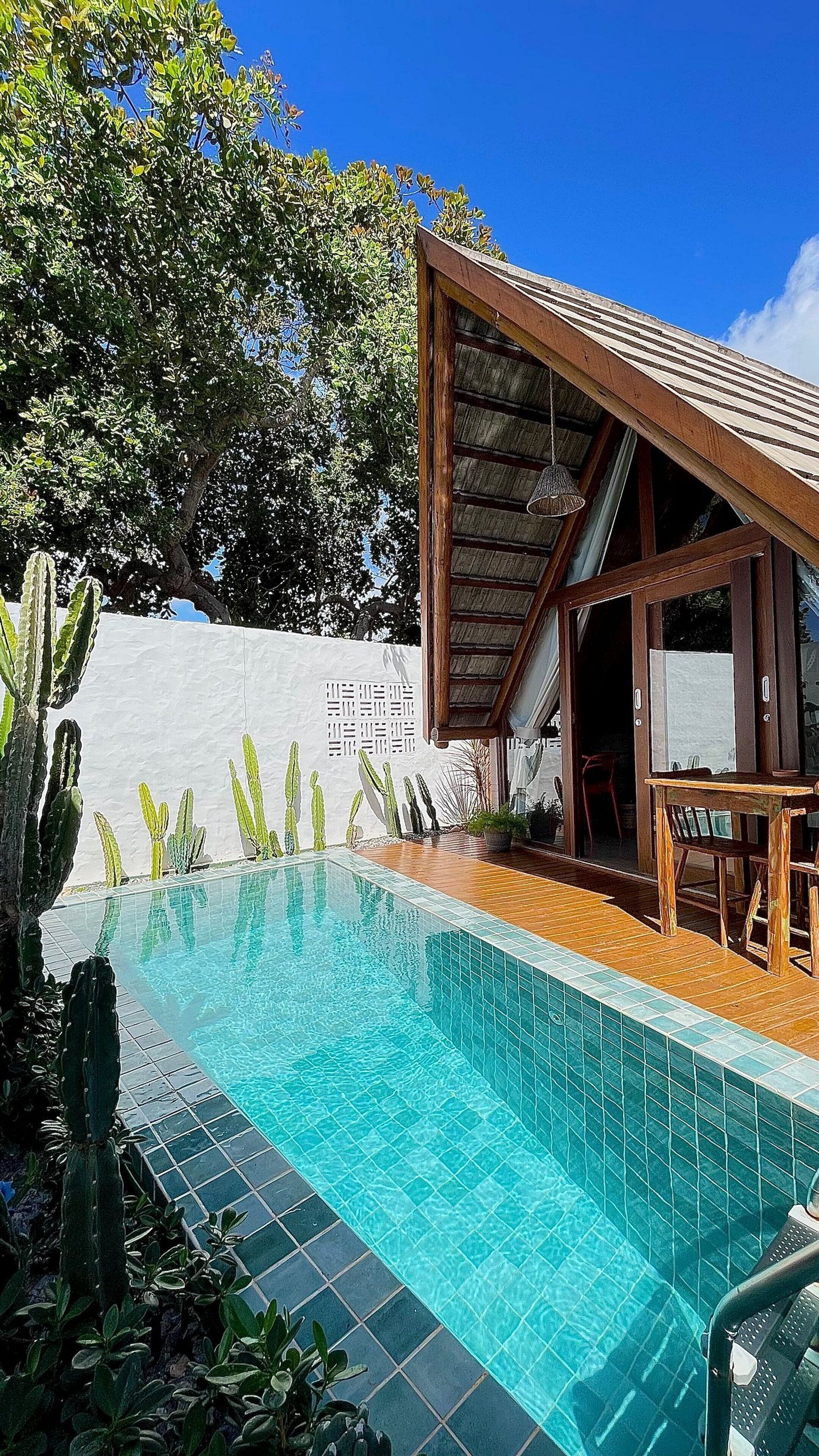 A swimming pool with a wooden deck and a covered seating area.