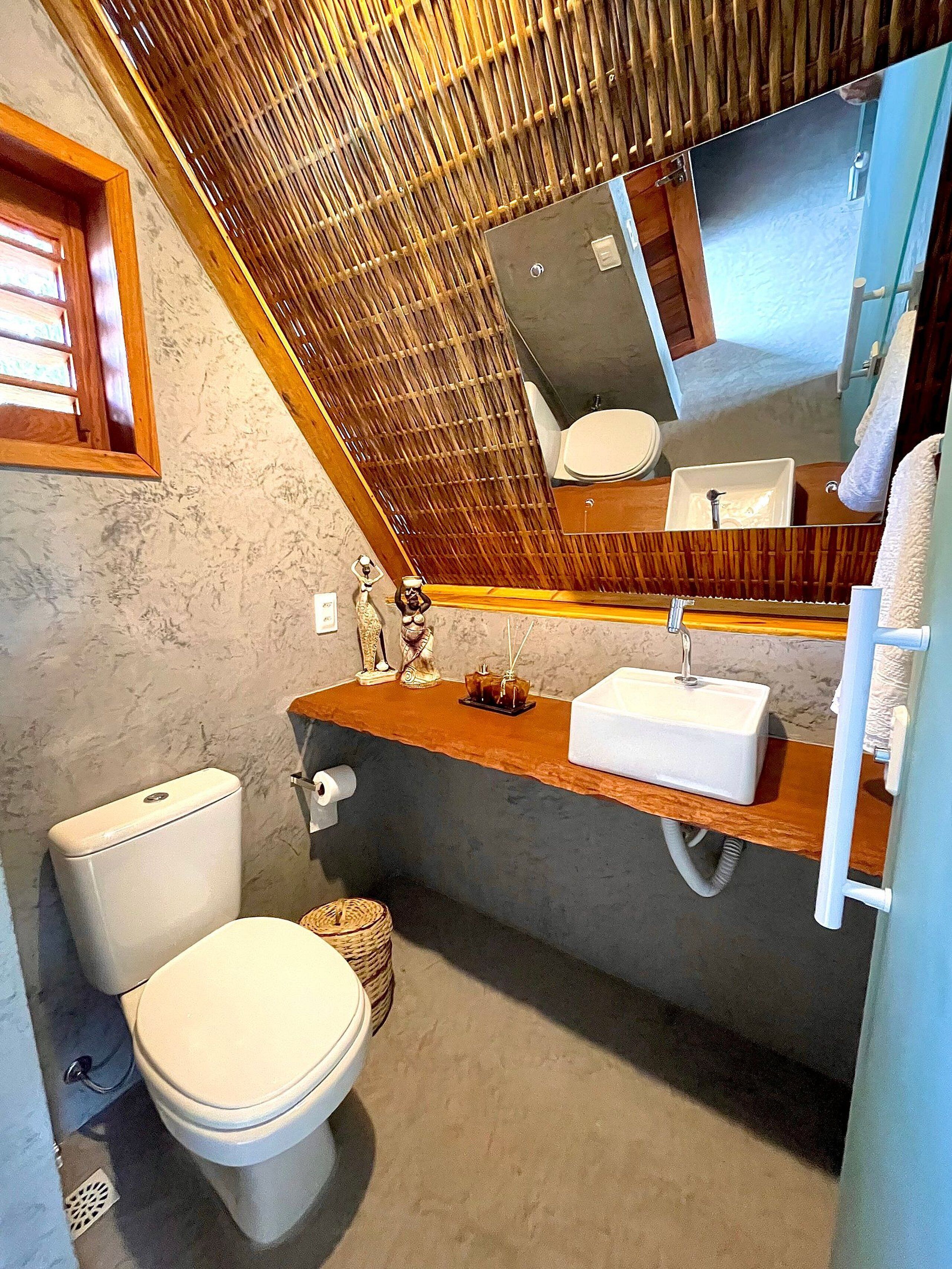 Et badeværelse med toilet, vask og spejl.