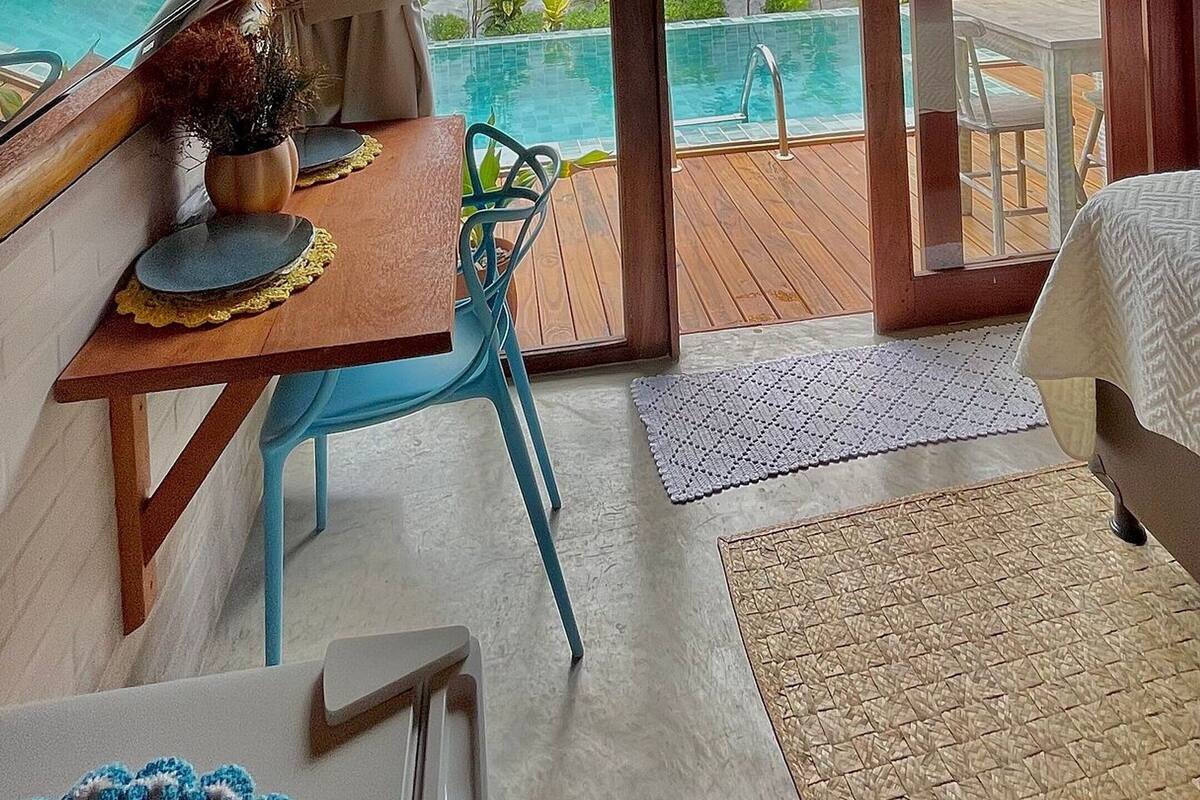 A cozy room with a wooden ceiling, a large window, and a view of a pool.