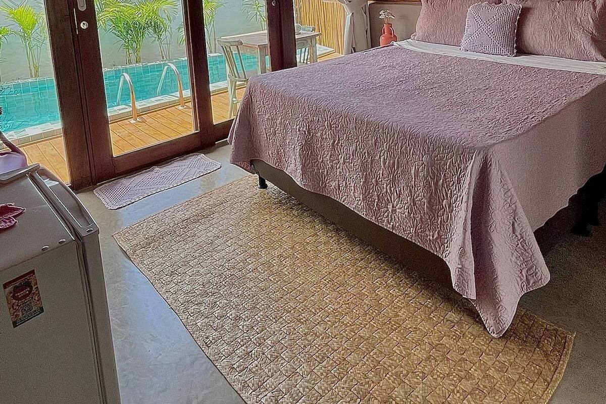 A bedroom with a large bed, a view of the sea, and a ceiling with a woven design.