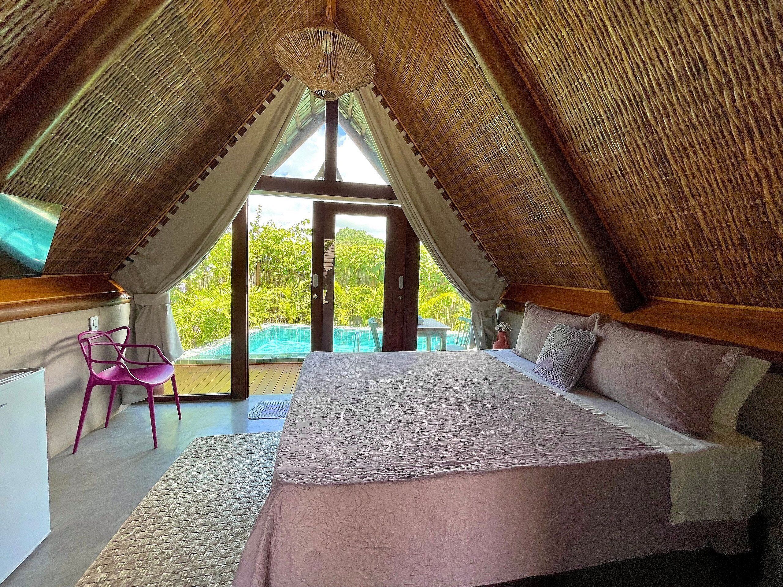 A bedroom with a large bed, a chair, and a view of a swimming pool.