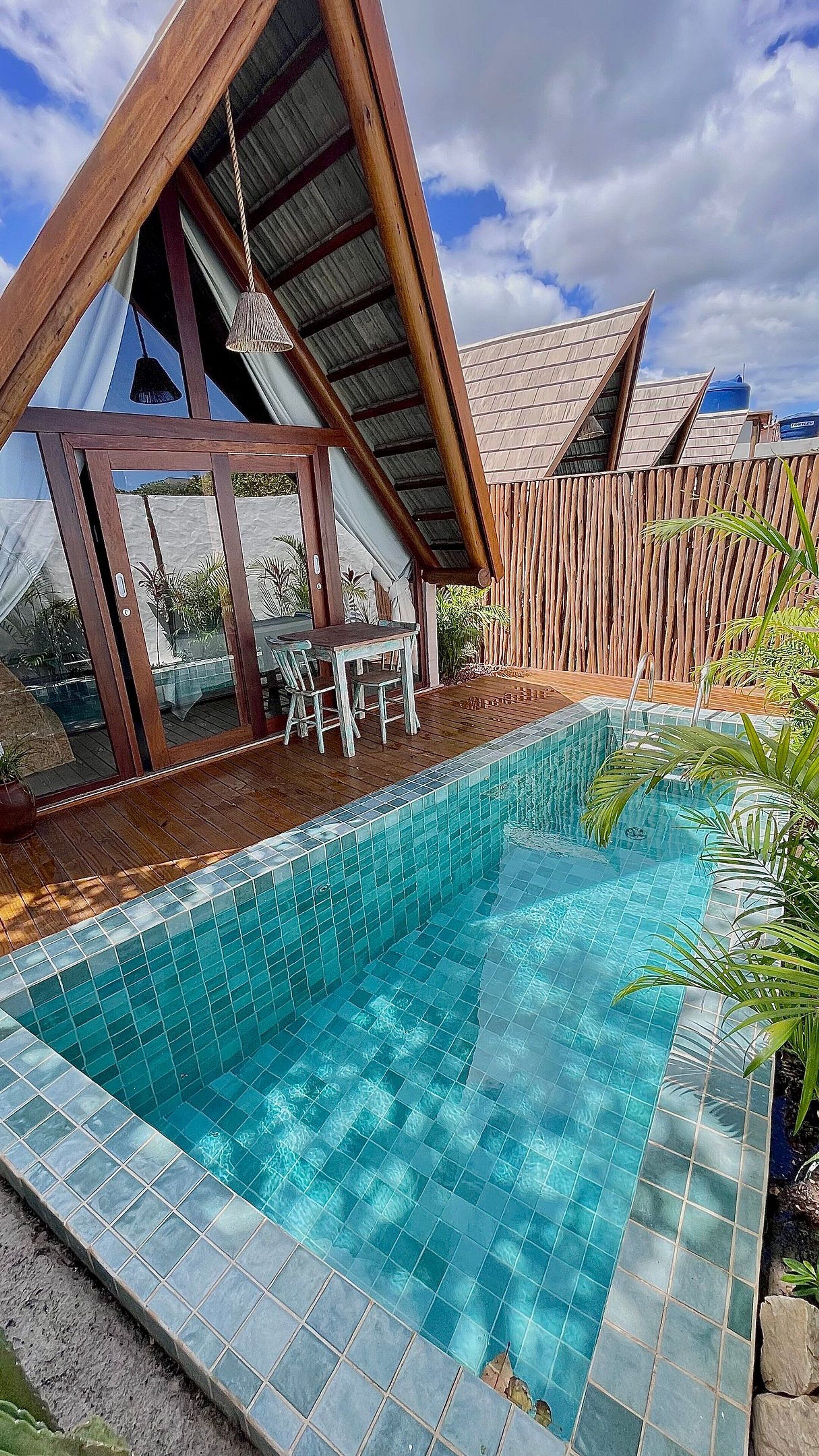 A swimming pool with a wooden deck and a covered seating area.