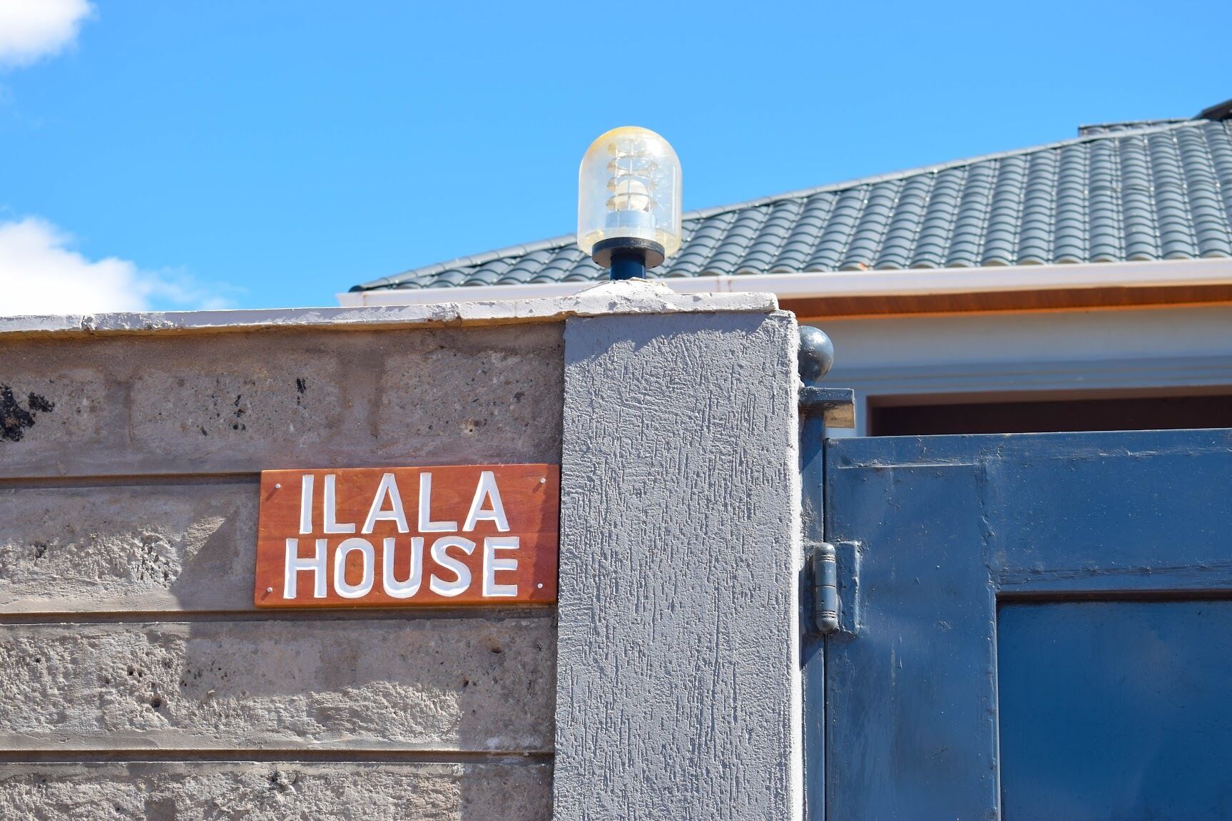 Rakennuksessa on kyltti, jossa lukee ”ILALA HOUSE”, ja siinä on sininen ovi.