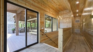Un intérieur en bois avec de grandes portes coulissantes en verre donnant sur un patio extérieur.