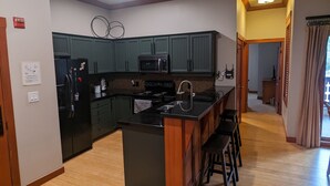 A modern kitchen with a central island, dark cabinets, and a microwave. - Beautiful End-Unit with Private Balcony and hot tub + pool. (Solitude)