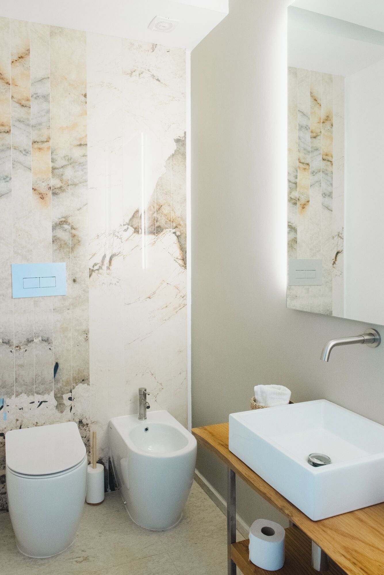 A modern bathroom with a bidet, a sink, and a mirror.
