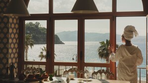 A room with large windows overlooking a coastal view, featuring a table with chairs and a person in a towel. - La Balza di Scilla (Scilla)