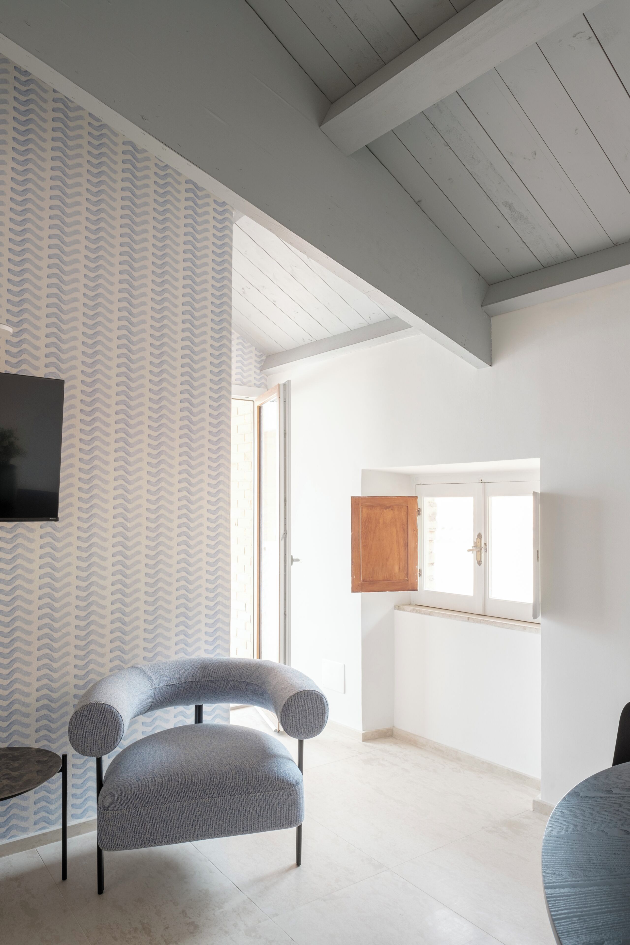 Un intérieur moderne avec un fauteuil gris aux lignes courbes, un meuble en bois et un sol carrelé.
