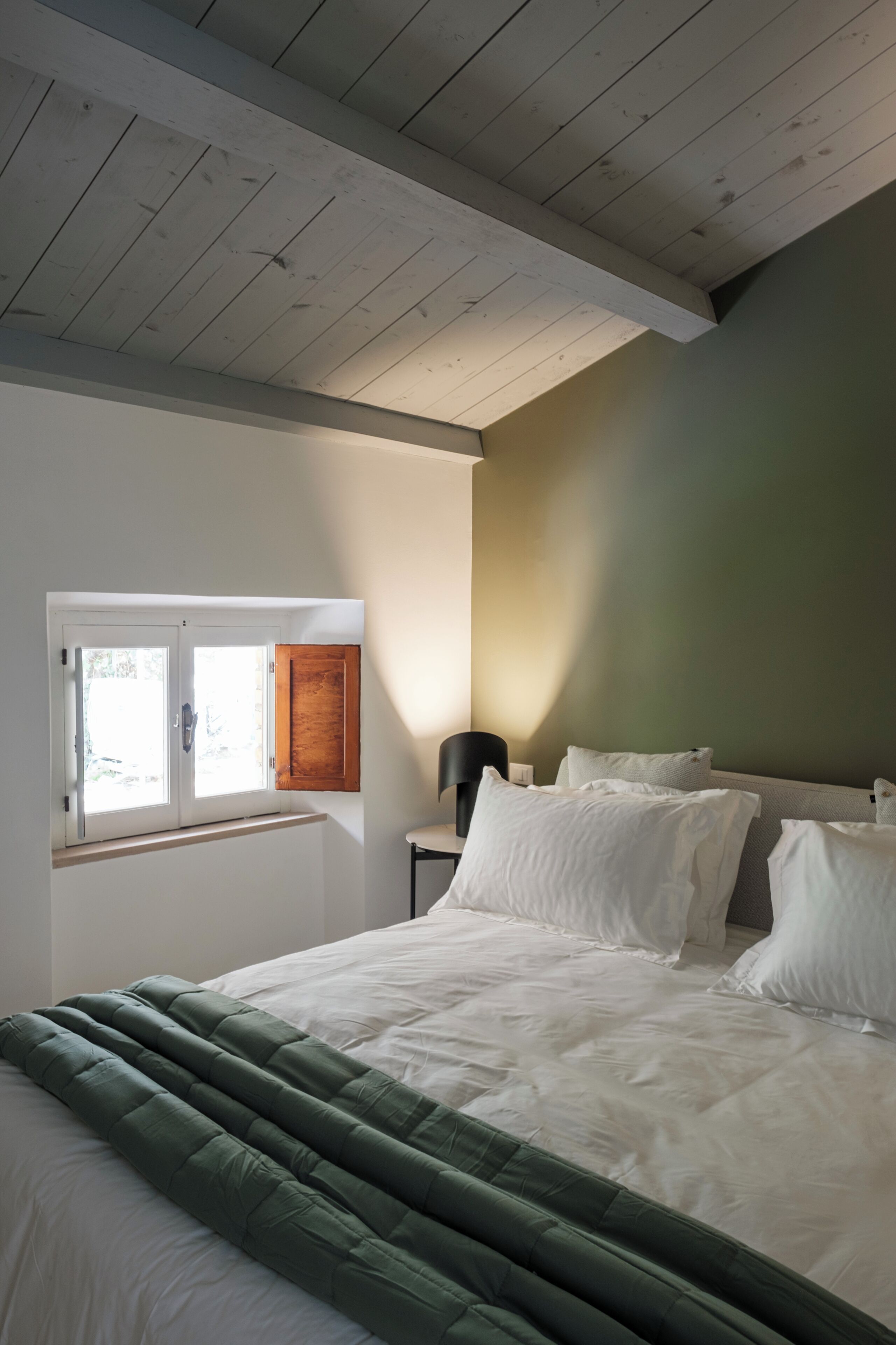 Quarto com cama, janela, mesa de cabeceira e abajur.