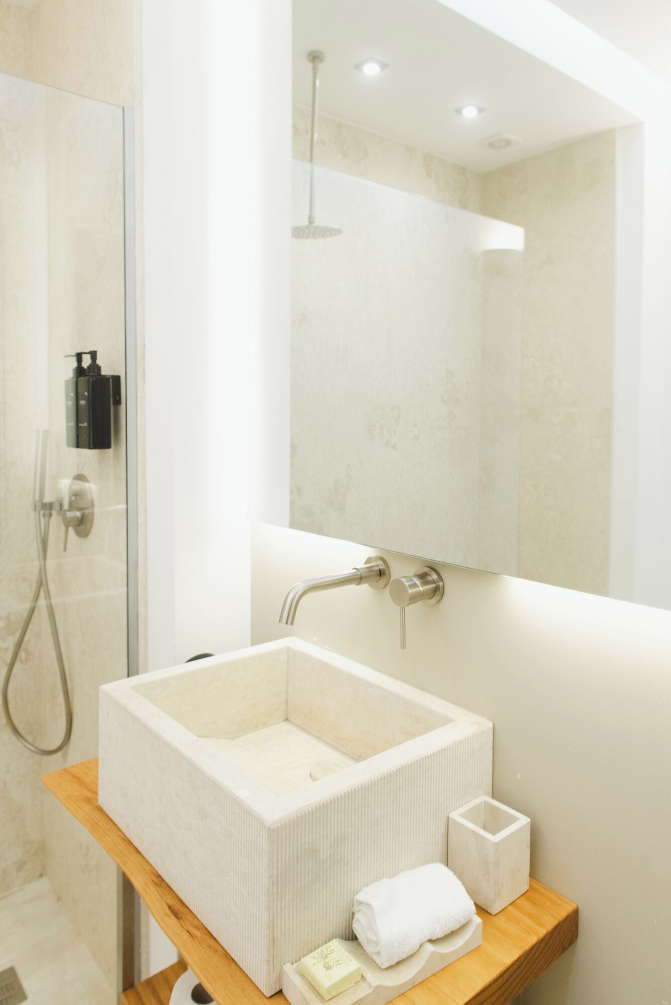 A modern bathroom with a large rectangular sink, a handheld showerhead, and a mirror above the sink.