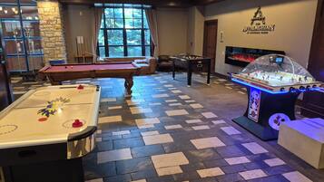 Una sala de recreación con mesa de billar, mesa de futbolín y mesa de hockey sobre hielo.