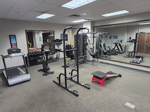 A gym with various exercise equipment, including treadmills, weight machines, and free weights.
