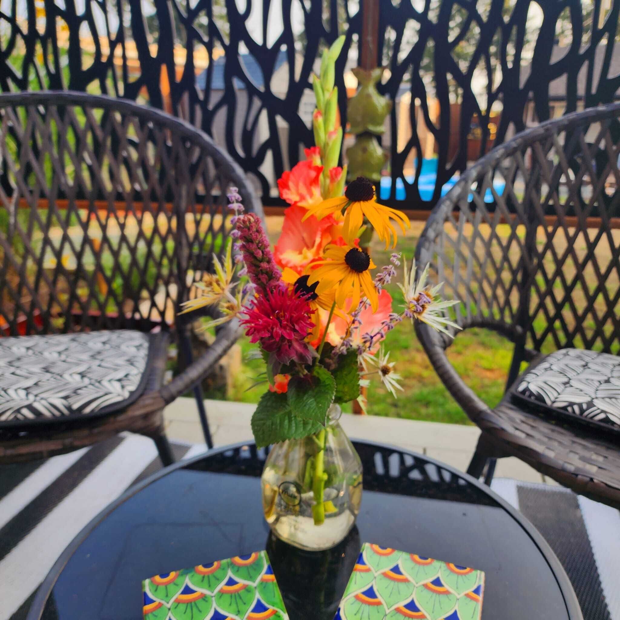 A table with a vase of flowers and a colorful placemat.