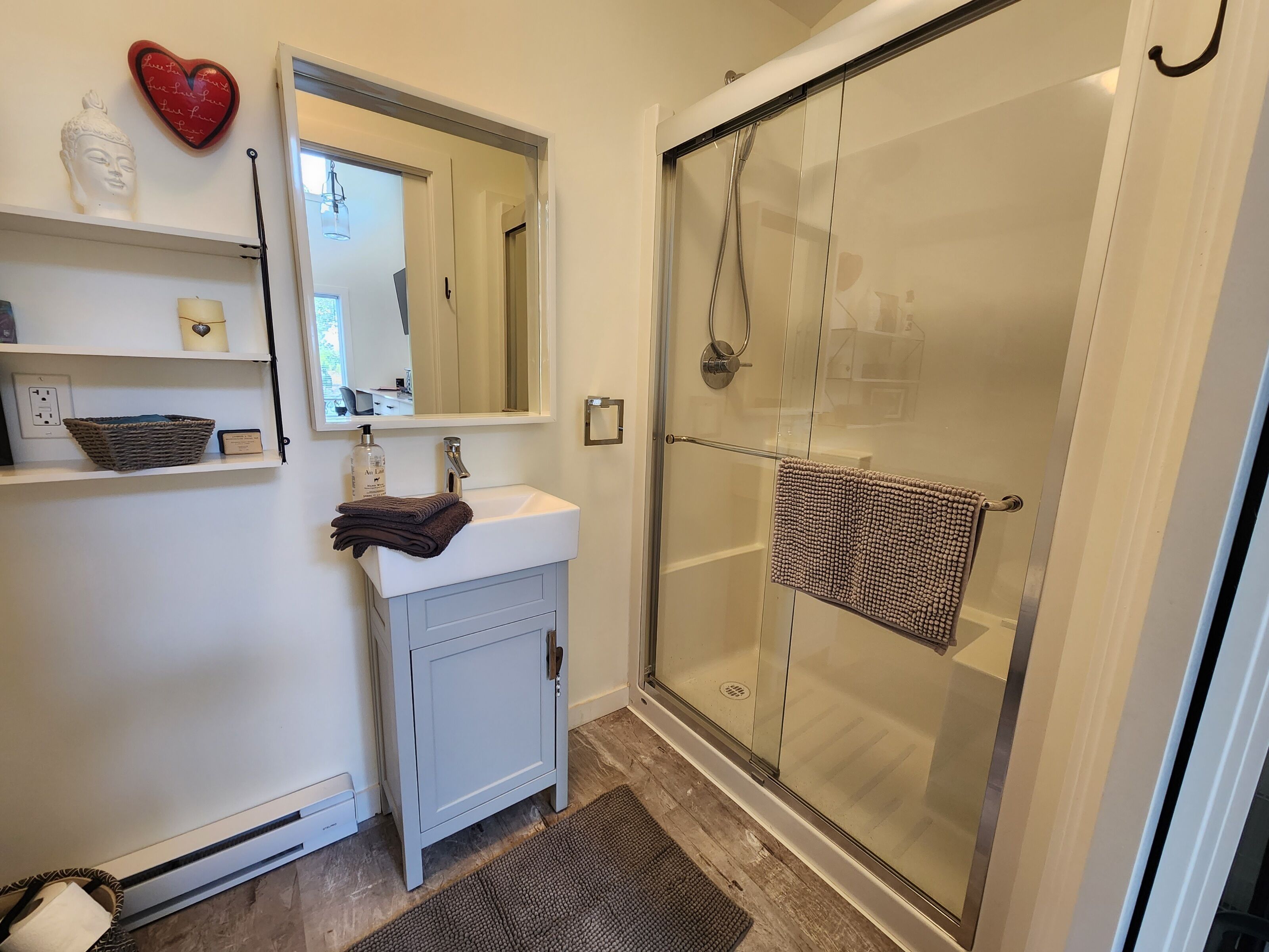 A bathroom with a white sink, mirror, and glass shower enclosure.