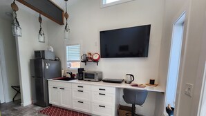 Une cuisine compacte équipée d’un réfrigérateur, d’un four à micro-ondes, d’un grille-pain et d’une machine à café.