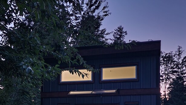 Une maison moderne à deux étages, dotée de grandes fenêtres et d’une porte d’entrée.