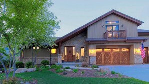 Une maison à deux étages avec une façade en pierre, une porte d’entrée en bois et un garage doté d’une grande porte en bois.