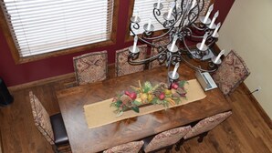 Une salle à manger avec une table en bois, des chaises à motifs, un lustre et un élément décoratif central.
