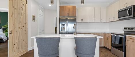 Una cocina moderna con una isla central, electrodomésticos de acero inoxidable y armarios de madera clara.