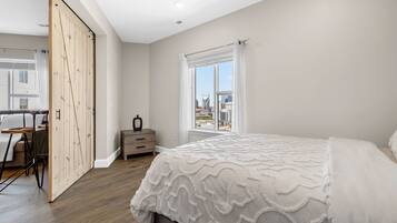 Ein Schlafzimmer mit einem großen Bett, einem Holzschrank, einem Schreibtisch mit Stuhl und einem Fenster mit Blick auf die Stadt.