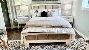 Un dormitorio con cama, mesitas de noche y ventana.