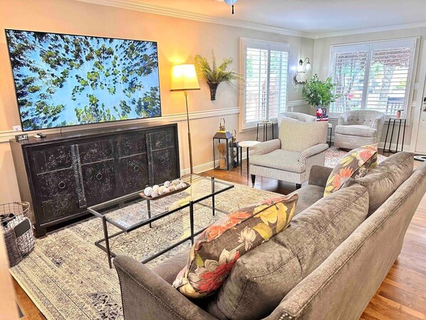 A living room with a fireplace, a sofa, a striped armchair, and a television. - Pleasant Downtown Haven *0.3 Miles *Pet Friendly (Prescott)