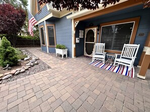 A blue building with a brick patio, white chairs, and an American flag.