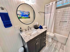 A bathroom with a marble sink, dark cabinets, a white toilet, and a shower with a white curtain. - Pleasant Downtown Haven *0.3 Miles *Pet Friendly (Prescott)