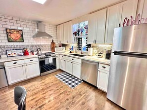 A modern kitchen with white cabinets, a stainless steel refrigerator, a microwave, and a stove. - Pleasant Downtown Haven *0.3 Miles *Pet Friendly (Prescott)