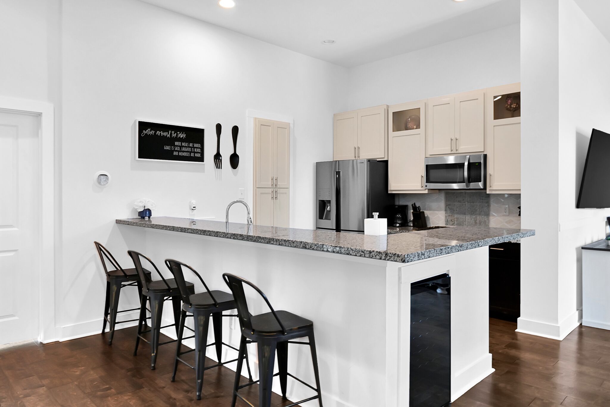 A modern kitchen with a central island, bar stools, and stainless steel appliances.