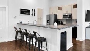 Una cocina moderna con una isla central, taburetes de bar y electrodomésticos de acero inoxidable.