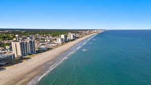 Un paisaje urbano costero con playa, rascacielos y cielo azul despejado.