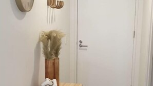 A hallway with a wooden console table, a clock, and a door. - Peaceful One Bedroom Residence with Parking (Brisbane)