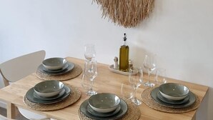 A dining table set with plates, glasses, and a bottle, surrounded by white chairs. - Peaceful One Bedroom Residence with Parking (Brisbane)