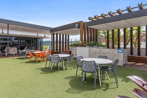 An outdoor patio area with tables and chairs, a pergola structure, and a view of the surrounding landscape.