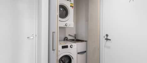 A compact laundry room with a washing machine, dryer, and a small sink.