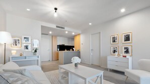 A modern living room with a sofa, coffee table, and a dining area. - Two Bedroom Two Bathroom | First Class Residence on Queen St, Brisbane CBD (Brisbane)