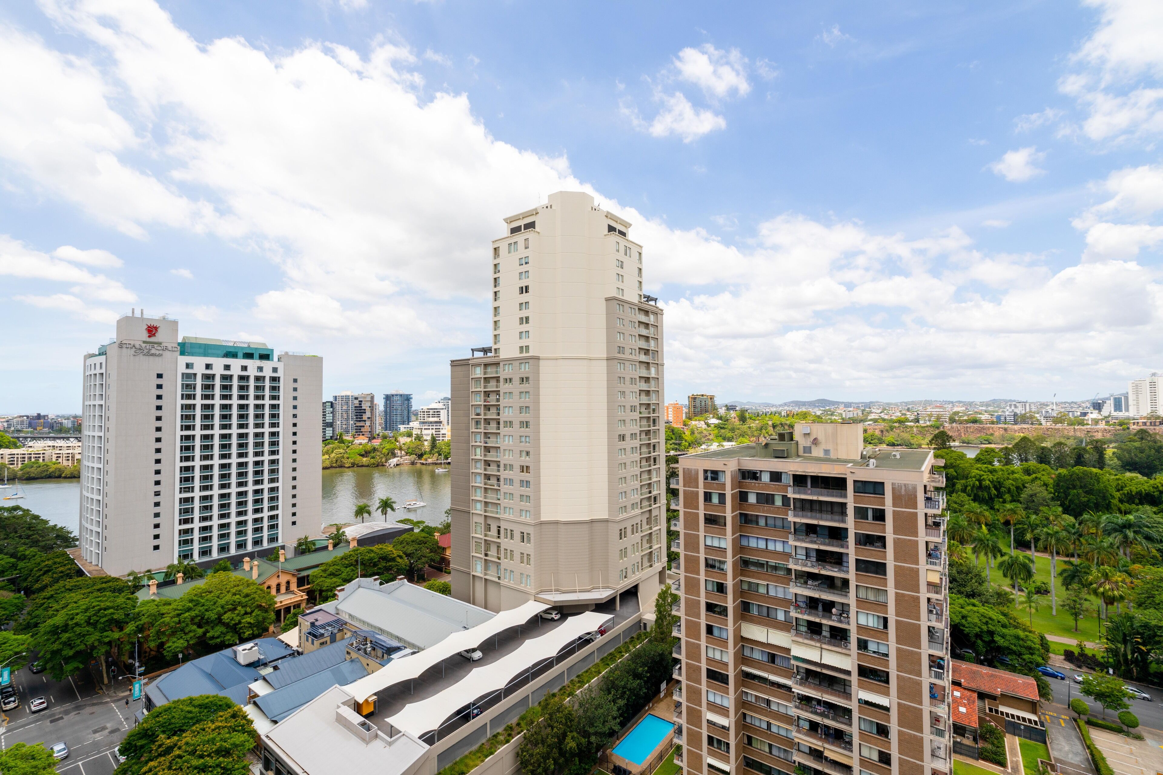 A high-rise building with multiple floors, a parking area, and a body of water in the background.