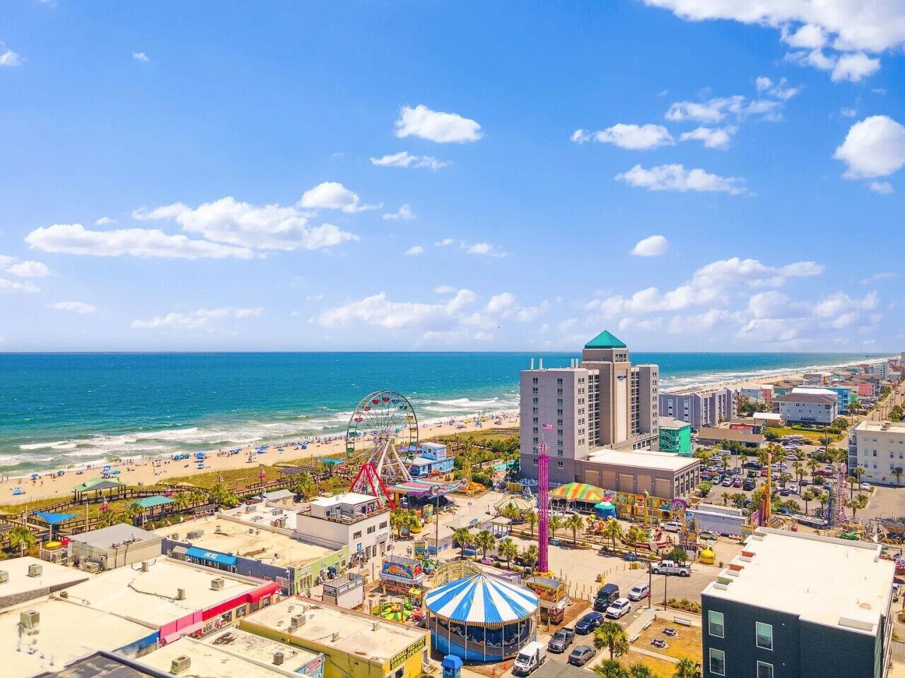 A coastal cityscape with a beach, a Ferris wheel, and a tall building with a green roof.
