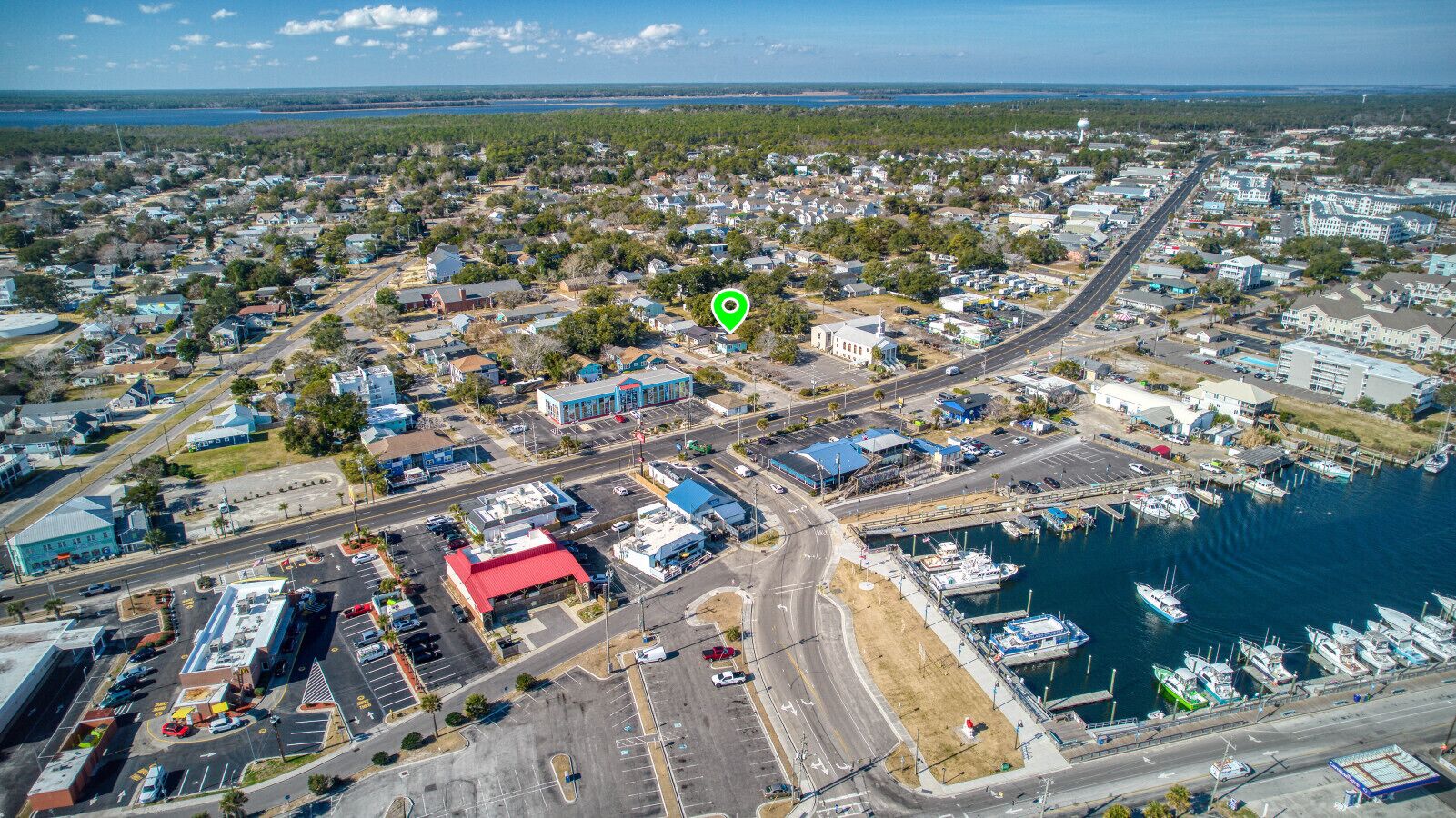 An aerial view of a coastal town with a marina, residential areas, and commercial buildings.