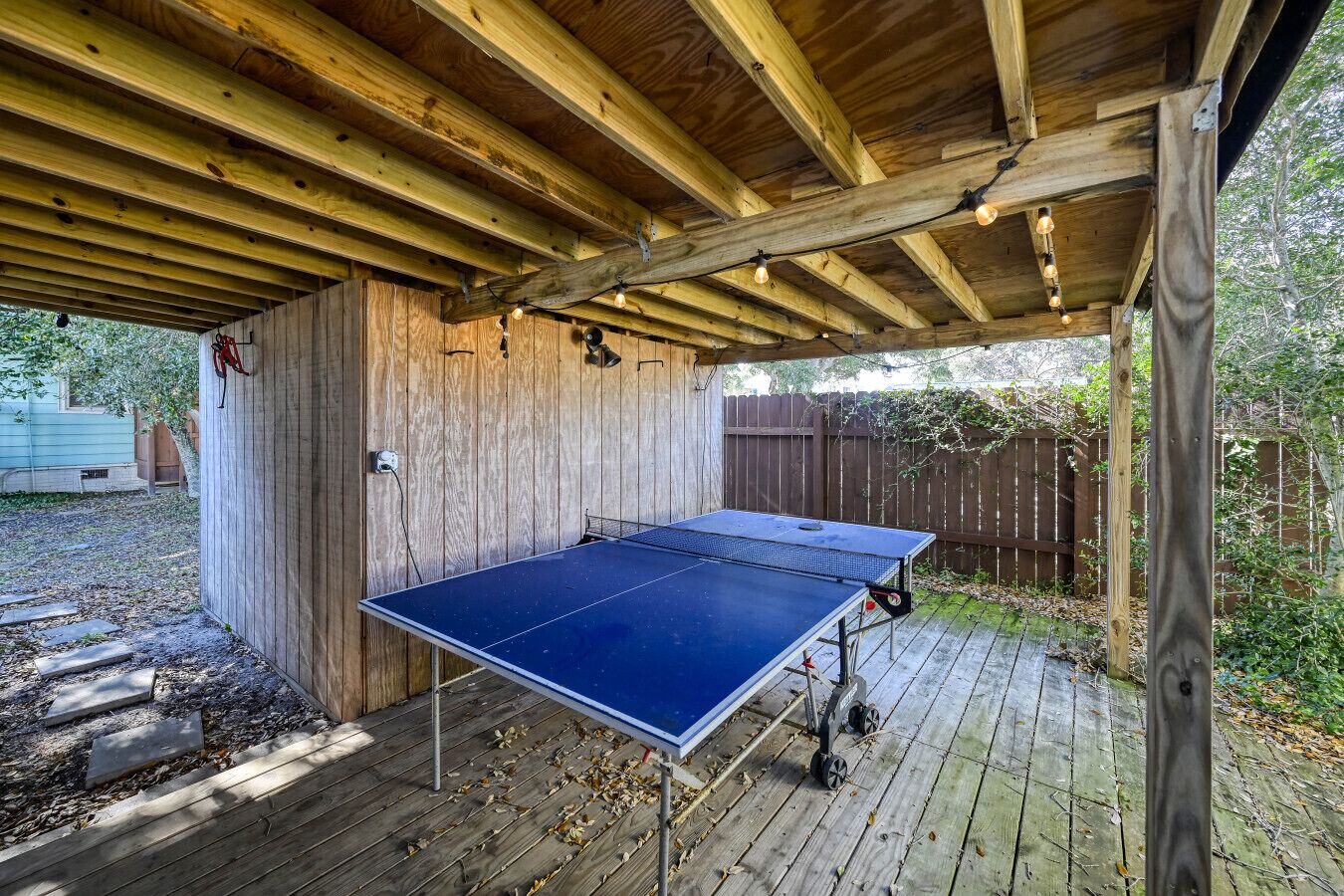 Una terraza de madera al aire libre con mesa de ping pong y otra más pequeña.