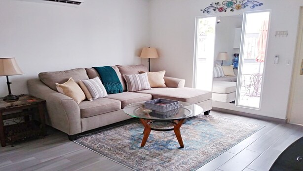 A living room with a sofa, a glass coffee table, and a patterned rug.