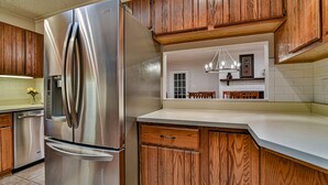 A kitchen with wooden cabinets, a stainless steel refrigerator, and a white countertop. - Forest Run - 4 Bedrooms with hot tub (Asheville)