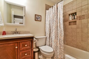 Une salle de bain équipée de toilettes, d’un lavabo, d’un meuble-lavabo et d’un rideau de douche.