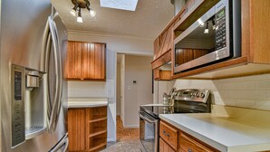 A kitchen with wooden cabinets, a stainless steel refrigerator, a microwave, and an oven. - Forest Run - 4 Bedrooms with hot tub (Asheville)