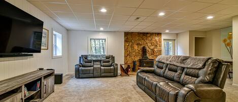 A living room with a stone wall, leather sofas, a flat-screen TV, and built-in shelves.