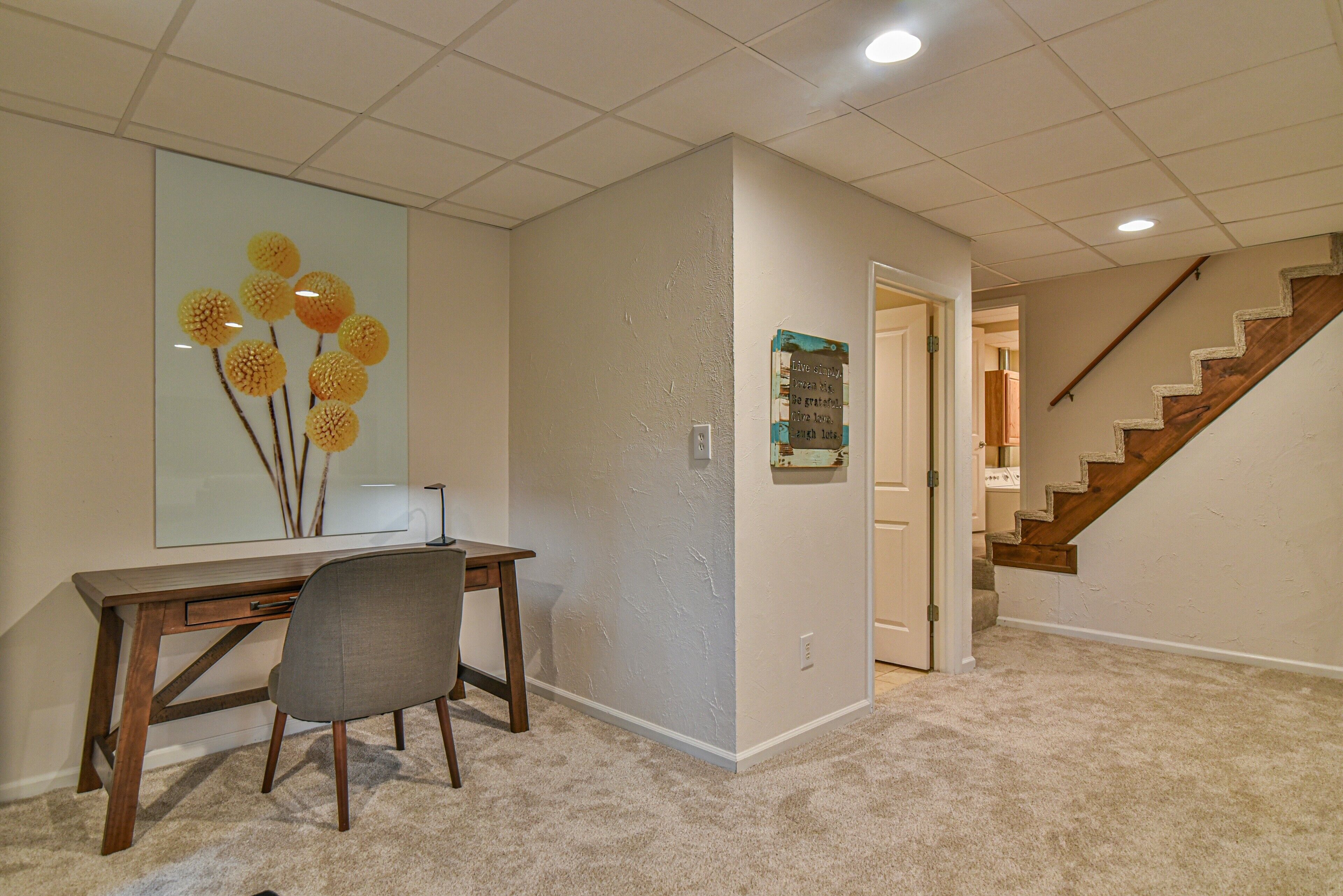 A home office with a desk, chair, and a large decorative piece on the wall.