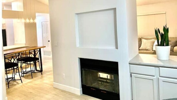 A modern living room with a fireplace, a dining area with chairs, and a kitchen with cabinets. - Cortaro Sweet Home-Quiet gated community  (Tucson)