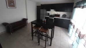 A compact kitchen with dark cabinets, a dining table with two chairs, and a bench in the corner. - Departamentos Velasco,a 10 min del Centro,ideal Para Conocer Tijuana (Tijuana)