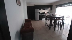 A compact kitchen with a dining area, a bench, and a refrigerator. - Departamentos Velasco,a 10 min del Centro,ideal Para Conocer Tijuana (Tijuana)